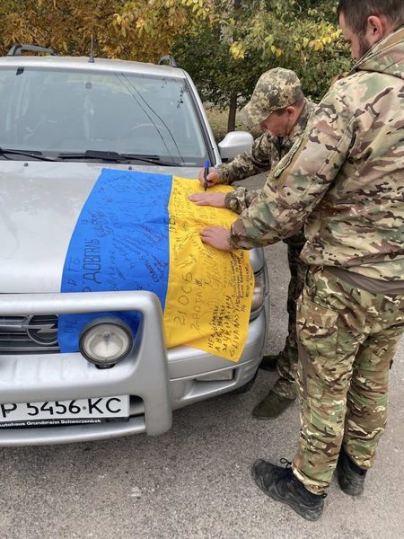 Підписання прапора на капоті переданого позашляховика.